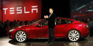 Elon Musk a lado de un Tesla rojo