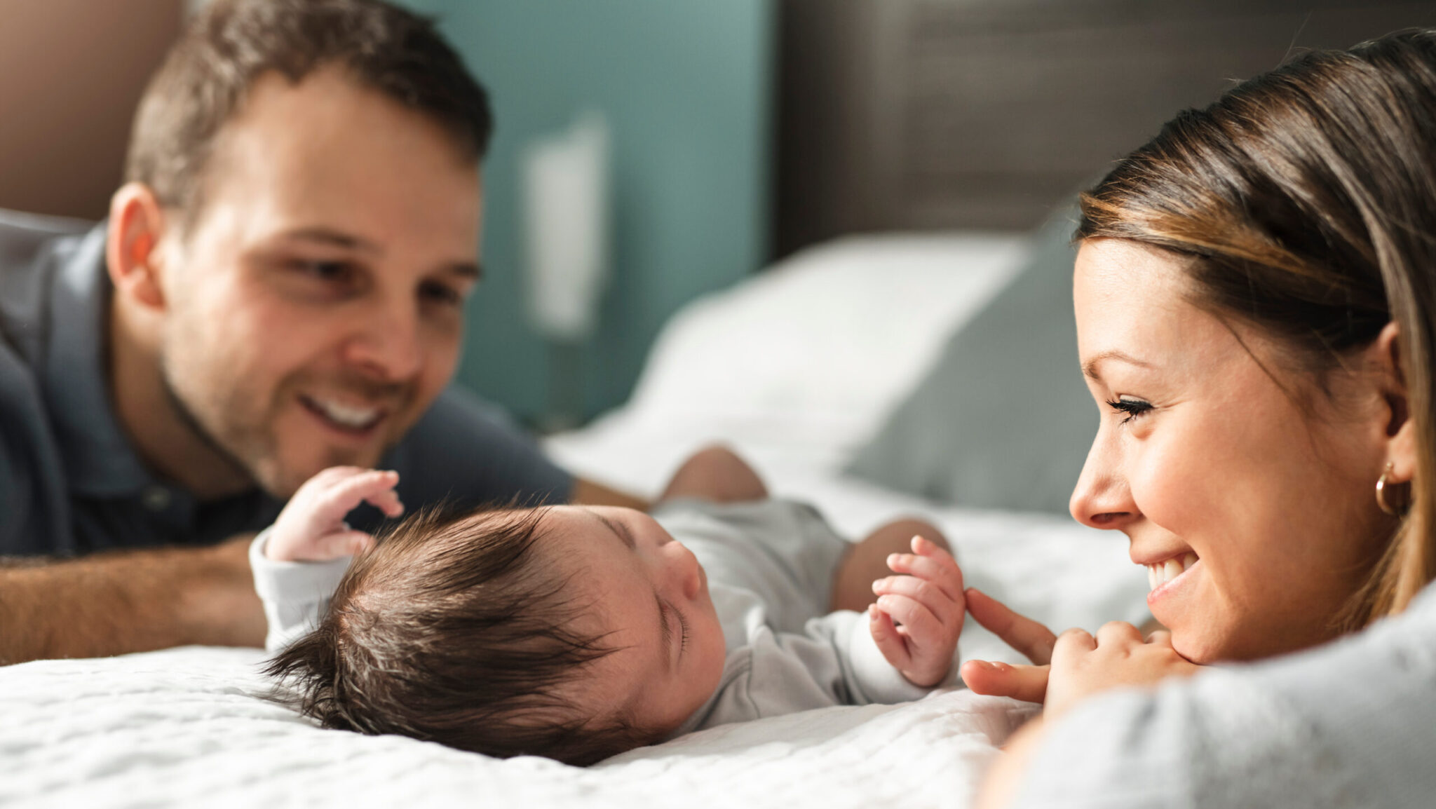 bebé acostado con sus papás mirandolo
